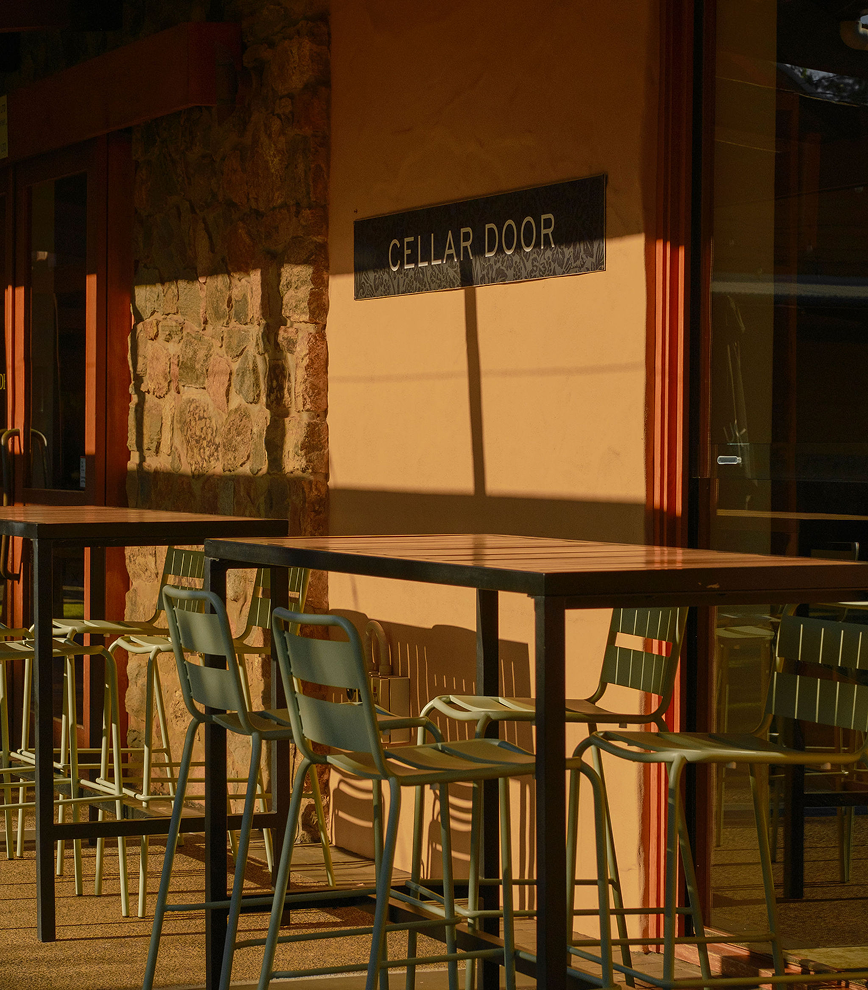 Cellar Door sign on a stone and rendered wall above outdoor tables and chairs