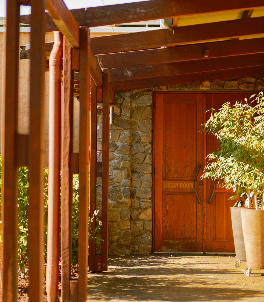 Timber walkway leading to the Lagan Room's stone entrance with wooden doors and a potted plant