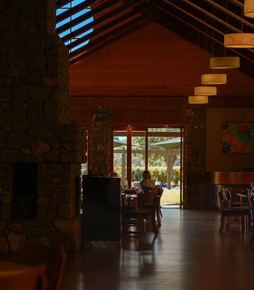 Interior of the Xanadu restaurant with vaulted timber ceiling, stone fireplace, and diners seated near an open door