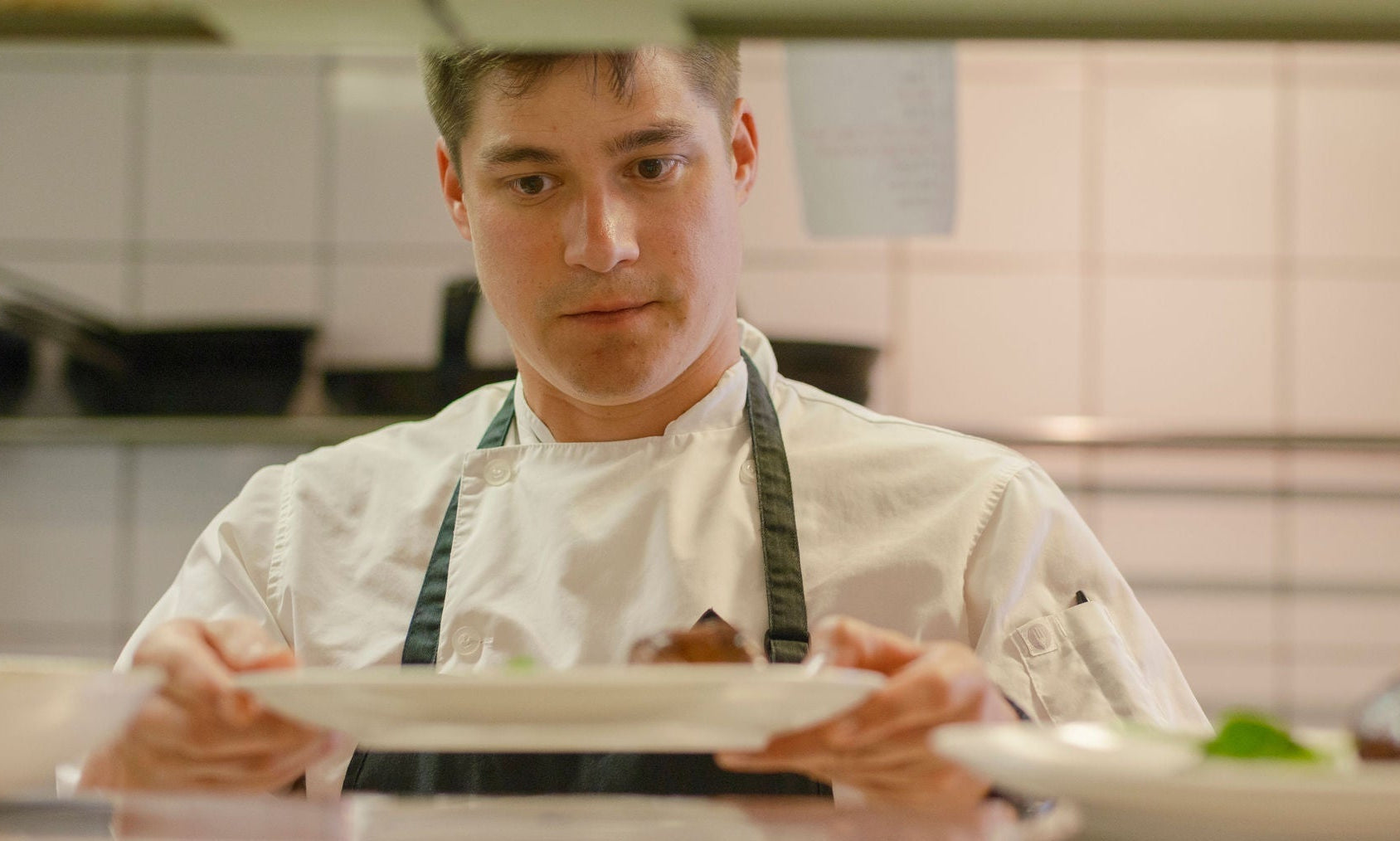 Xanadu restaurant chef holding a plated dessert in the kitchen