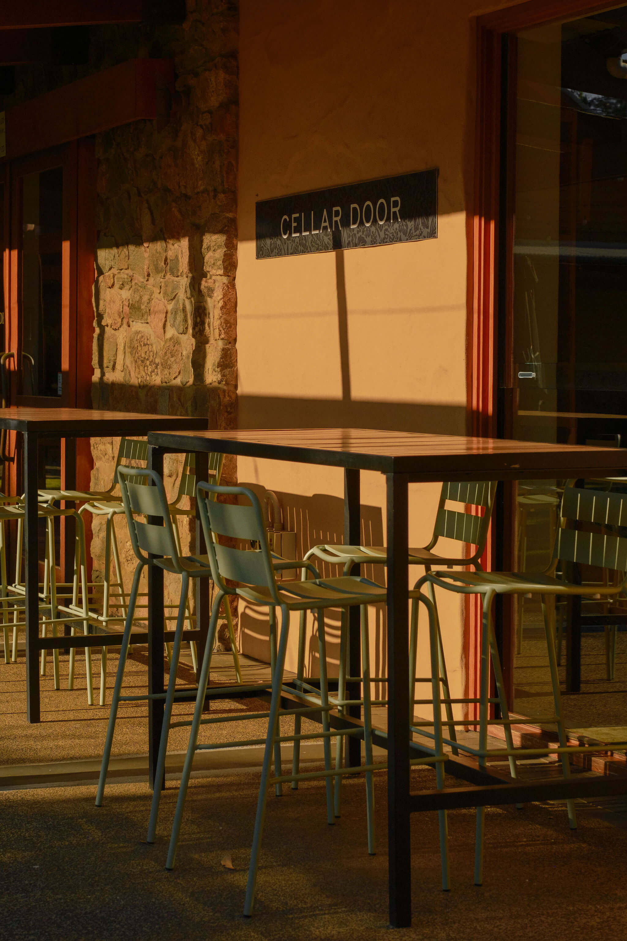 Outdoor cellar door seating area with high tables and chairs beneath the Cellar Door sign