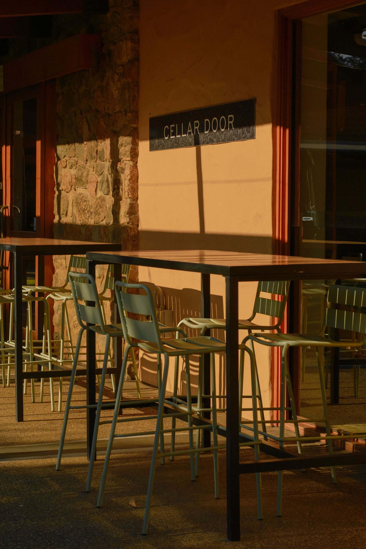 Outdoor cellar door seating area with high tables and chairs beneath the Cellar Door sign