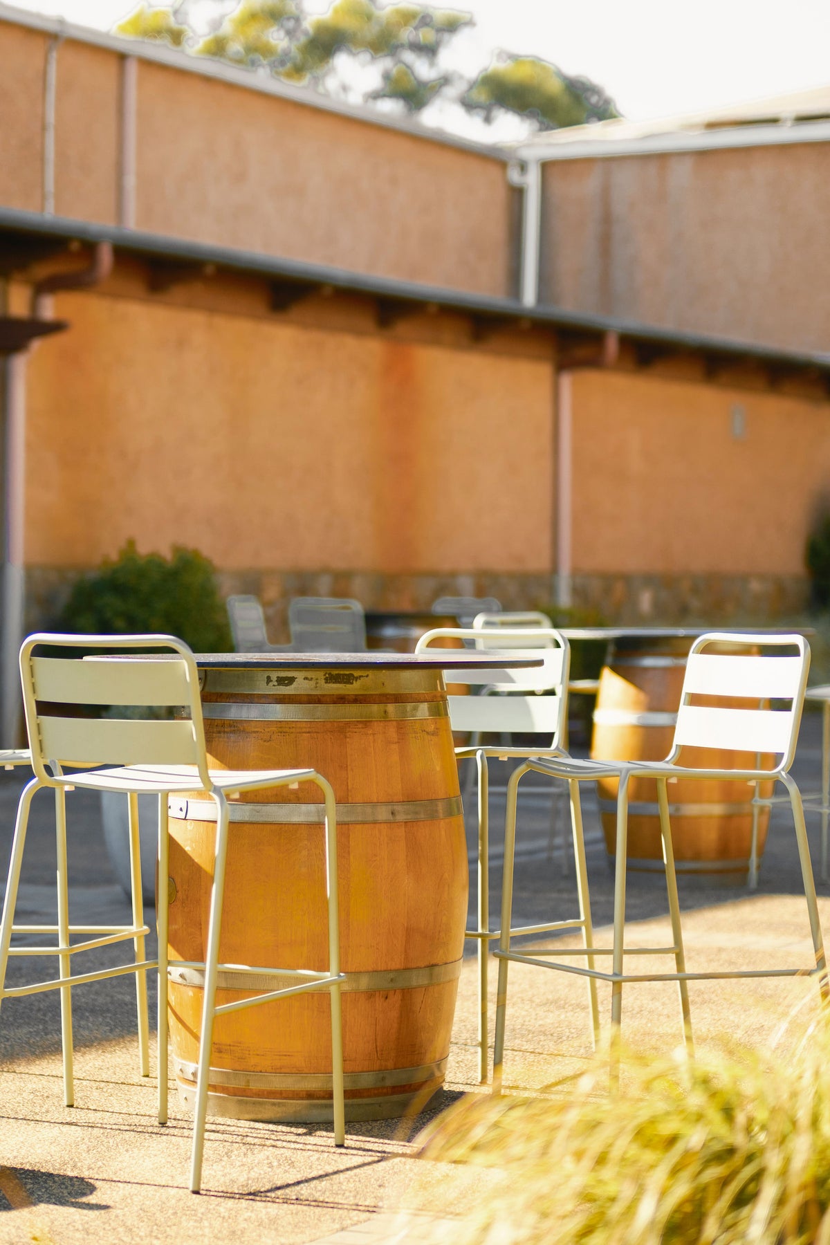 Outdoor seating area with wine barrel tables and chairs beside the winery building