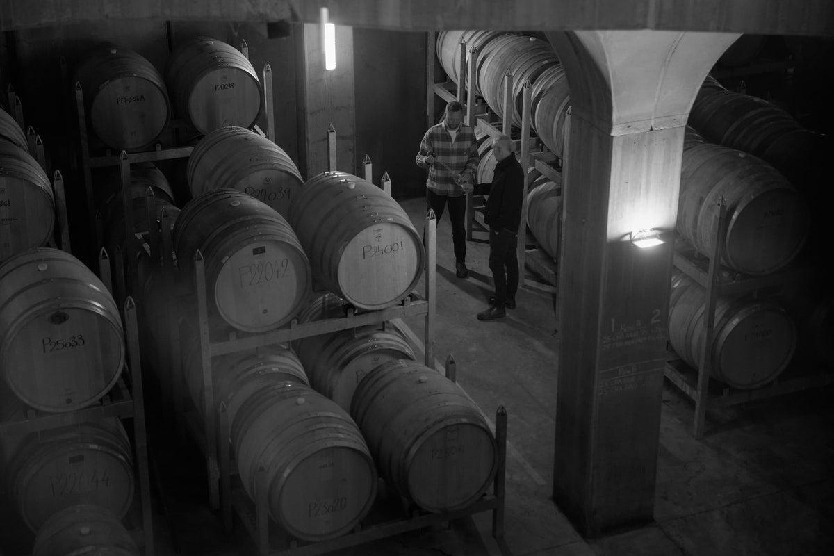 Black and white photo of two people examining oak barrels in the Yering Station barrel hall