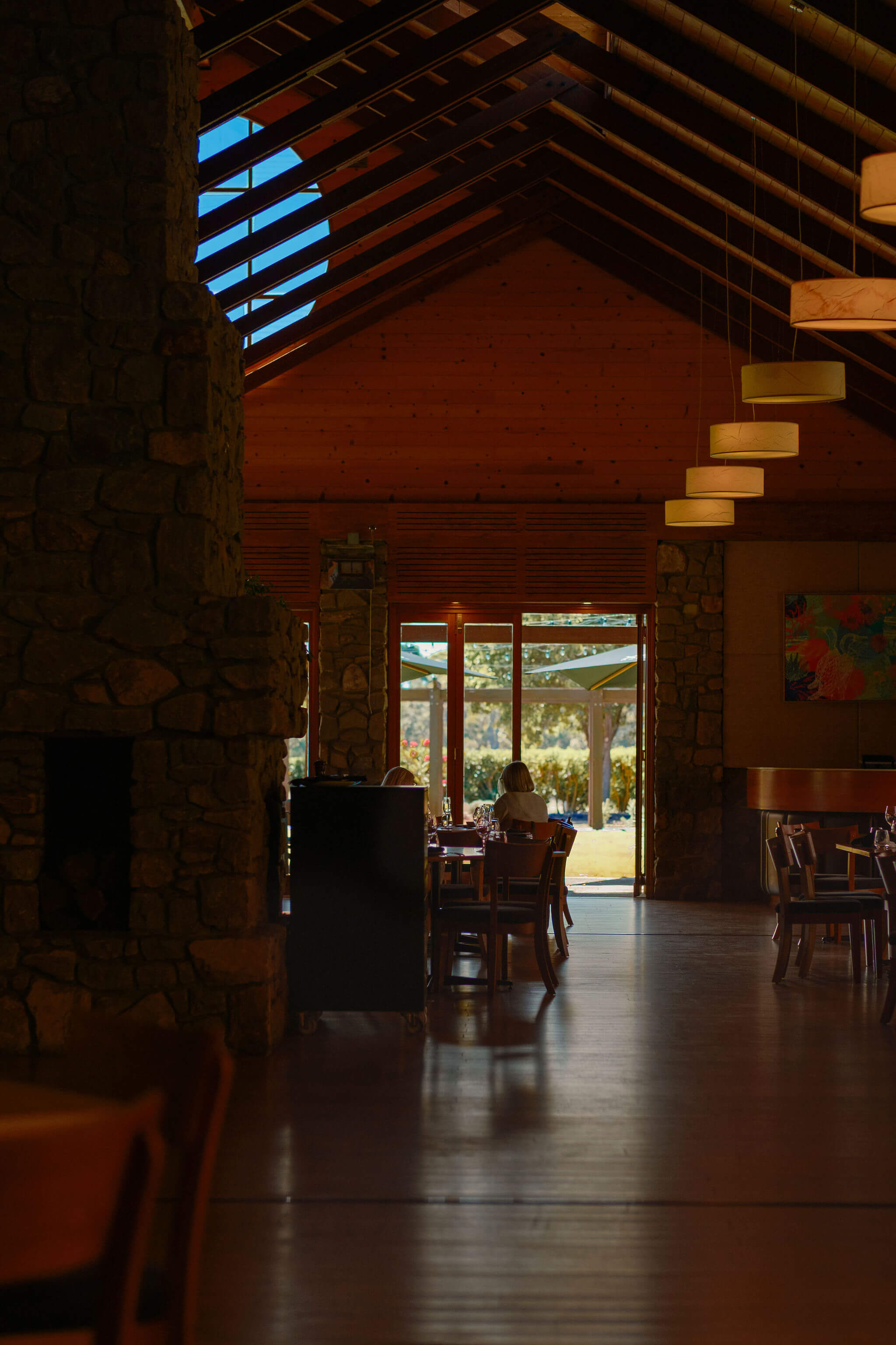 Interior of the Xanadu restaurant with vaulted timber ceiling, stone fireplace, and diners seated near an open door
