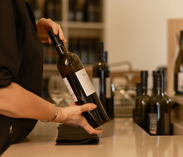 Cellar door staff member holding a bottle of Xanadu wine at the tasting bar