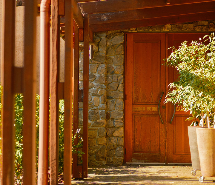 Wooden doors of the Lagan Room entrance framed by a stone wall and potted plants