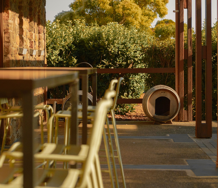 Outdoor terrace with a wine barrel repurposed as a small dog kennel beside a hedge