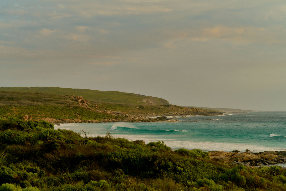Coastal Margaret River landscape with waves breaking near a rocky headland at sunset