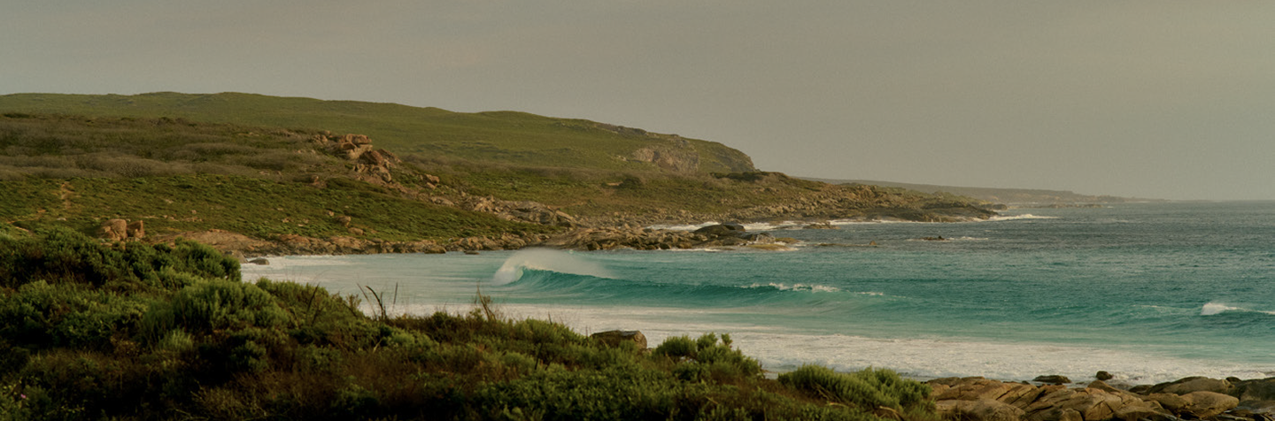 Coastal Margaret River landscape with waves breaking near a rocky headland at sunset