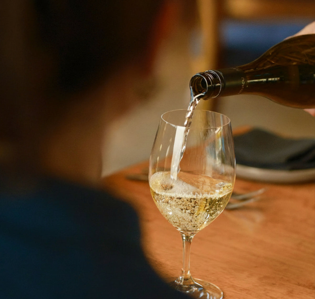 Waiter pouring a glass of white wine at a restaurant table